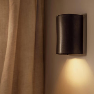 Handmade Shimmering Ceramic Wall Light slate short lit up on a beige wall side view