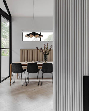 Modern dining room with a wooden pendant, a table, chairs, and a vase with flowers.