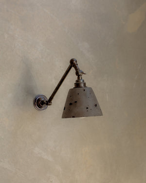 Concrete wall lamp with a long arm on a textured beige wall