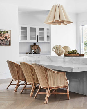 Modern kitchen with marble island, rattan chairs, and pendant light.