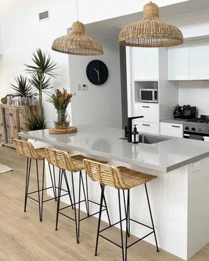 Modern kitchen with white island, bar stools, and bamboo pendant lights.