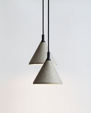 Two concrete pendant lights hanging against a light gray background