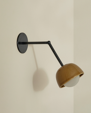 Wall-mounted lamp with a brown shade and black arm on a beige wall.