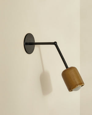 Wall-mounted lamp with brown shade and black arm on a beige wall