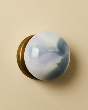 Round glass light with brass base on a beige background