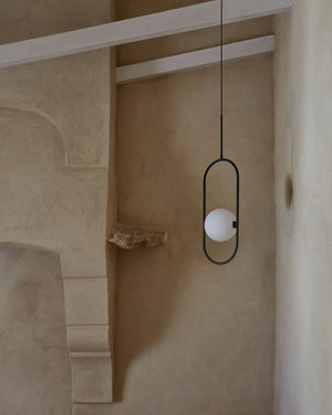 Minimalist pendant light hanging in a room with beige walls and architectural details.