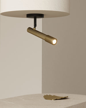 Modern ceiling light fixture with a gold cylindrical shade on a neutral background