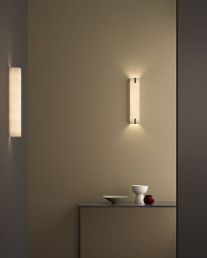 Two wall-mounted lights on a neutral wall with a shelf below.