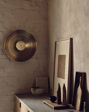 Decorative items including a large Disc Orb Wall Light, framed artwork, and wooden cutting boards against a stone wall.
