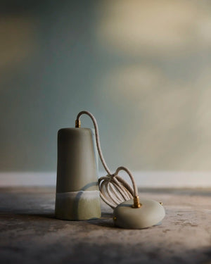 Ceramic Dusked Pendant light fitting with a cord on a textured surface