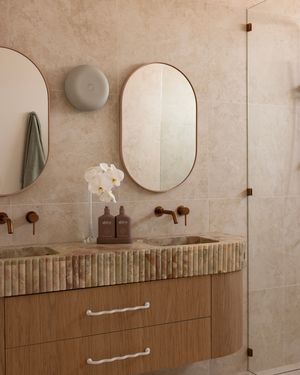 Bathroom vanity with stone countertop, mirrors, and decorative elements - ceramic wall sconce