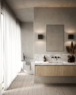 Modern bathroom with marble countertop, black wall lights and large mirror.