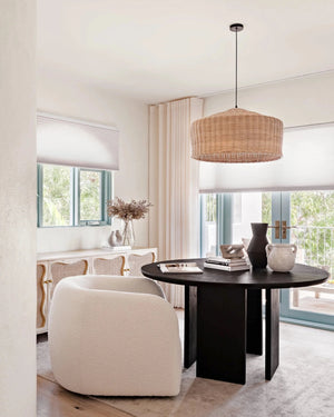 Modern living room with a round black table, white armchair, and rattan natural pendant