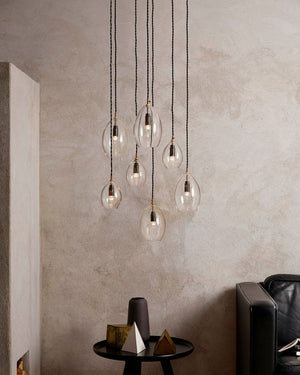 Modern pendant light fixture with clear glass bulbs hanging against a textured wall | Lighting Collective
