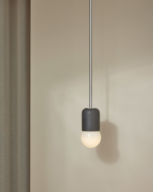 Minimalist pendant light with a black fixture and white bulb on a neutral background