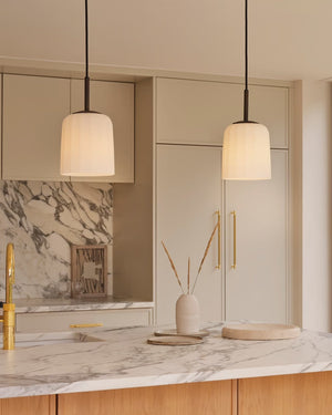 two white fluted pendant lights hanging above marble kitchen countertop light on