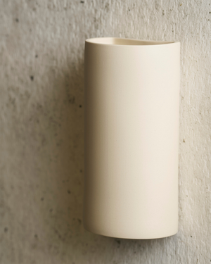 Beige cylindrical wall sconce on a textured wall