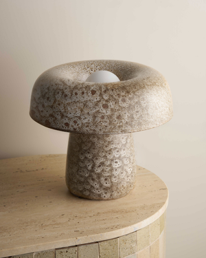 Stylised stone mushroom lamp on a wooden surface with a neutral background