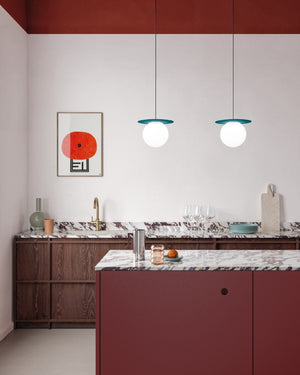 Modern kitchen with red island, marble countertops, and pendant lights.