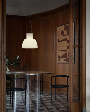 Italian Pendant suspended above dining room with a round table, black chairs, and a pendant light.