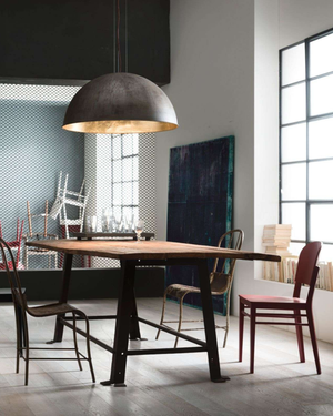 Dining area with a wooden table, brass dome pendant and chairs in a modern interior setting.

