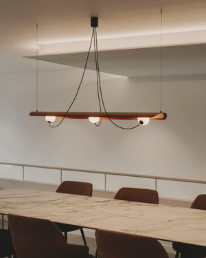 Modern magnetic acoustic linear  hanging above a marble table with chairs in a minimalistic setting.