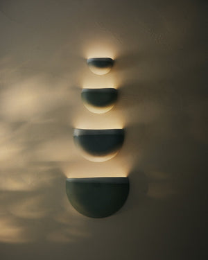 Wall-mounted light fixture casting shadows on a textured wall