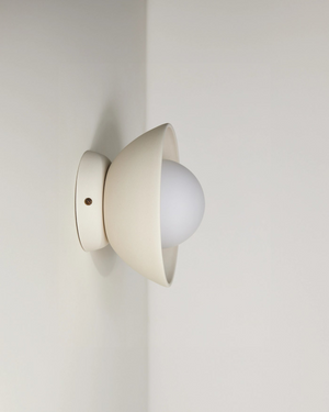 Wall-mounted light fixture with a white bulb on a plain wall