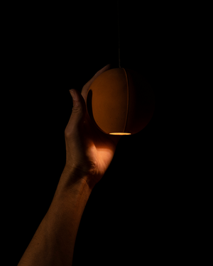 Hand holding a glowing pendant light against a dark background