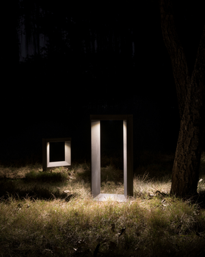 Two outdoor light fixtures in a grassy area at night.