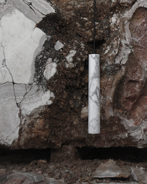 Marble-textured cylindrical pendant hanging against a rocky background