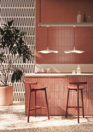 Modern kitchen with red tiled walls, white pendant lights, and wooden bar stools.