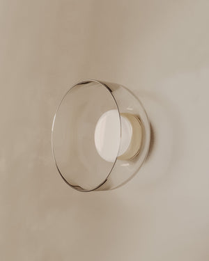 Round wall light fixture with glass shade on a beige wall