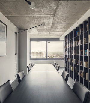 Potence Wall Light in a modern conference room with a long table and chairs, large window, and bookshelf.