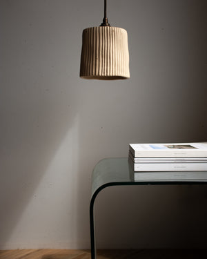 Beige pendant light hanging above a glass table with books