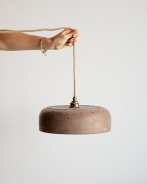 Person holding a concrete pendant light with a neutral background
