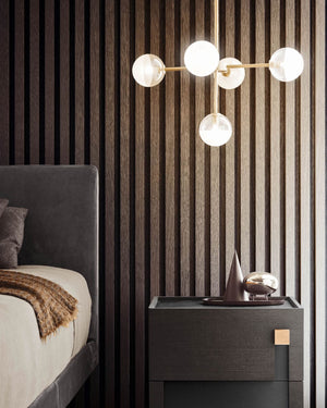 5 light modern chandelier placed next to a bed over a bedside table