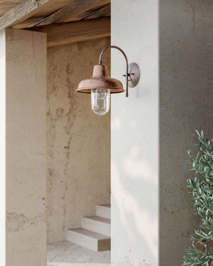 Copper curved wall light displayed outside near stairs of a rustic house