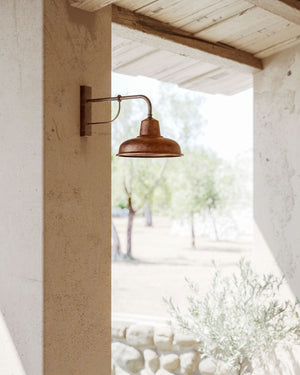 Copper straight wall light displayed outside of a rustic house