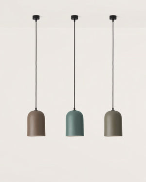 Three pendant lights in different colors hanging against a light gray background