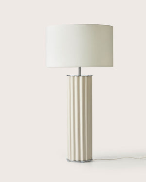 Table lamp with a cylindrical cream base and white shade on a light background