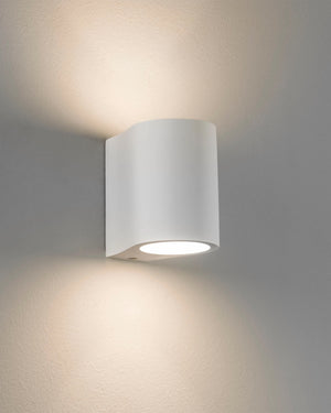 White plaster cylindrical wall light fixture on a grey wall