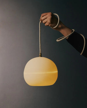 Hand holding a ceramic pendant light against a dark background