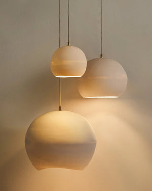 Three ceramic pendant lights hanging against a neutral background