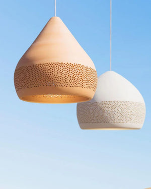 Two ceramic pendant lights with perforations on the bottom of the shade. One terracotta one white.