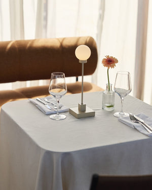 Dining table setting with glasses,Portable Mid-Century Modern Orb Table Lamp and a flower arrangement in a restaurant.