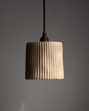 Cylindrical pendant light with ribbed texture on a gray background