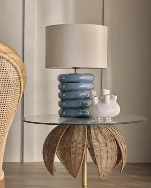 Decorative table with a blue lamp and wicker chair in a room setting
