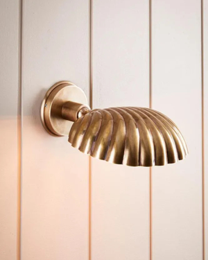 Brass wall sconce on a light wooden panel background | Lighting Collective
