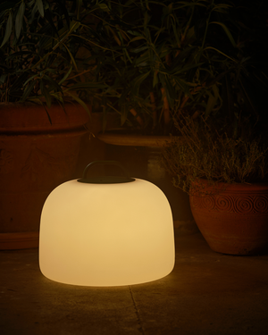 Glowing white outdoor lamp with potted plants in the background
